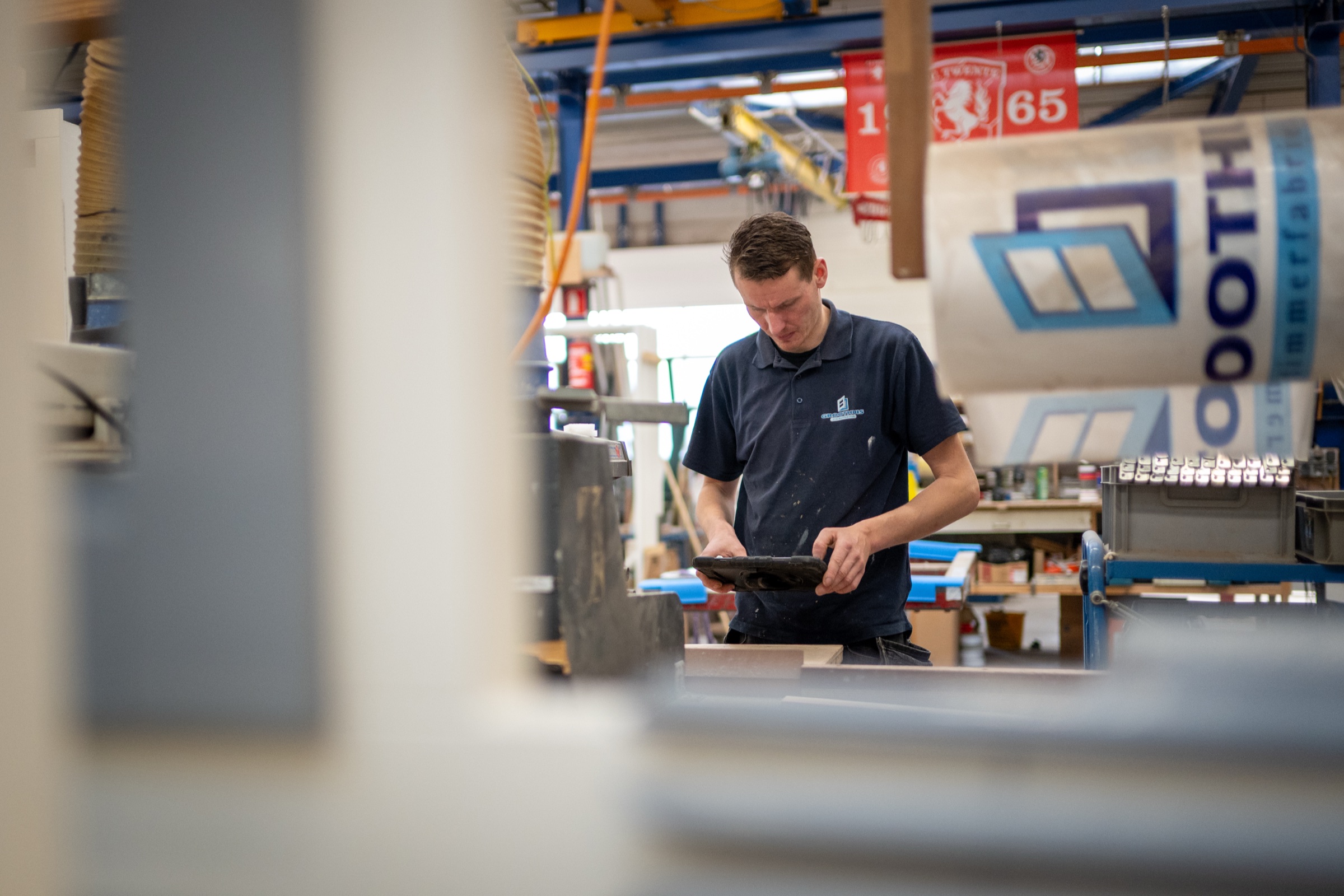 Medewerker bij Groothuis met iPad, gezien door fabrieksmachines
