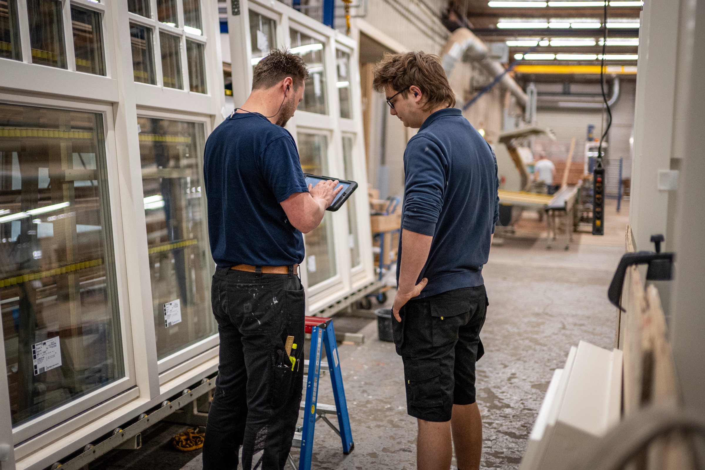 Twee medewerkers met iPad tussen kozijnen